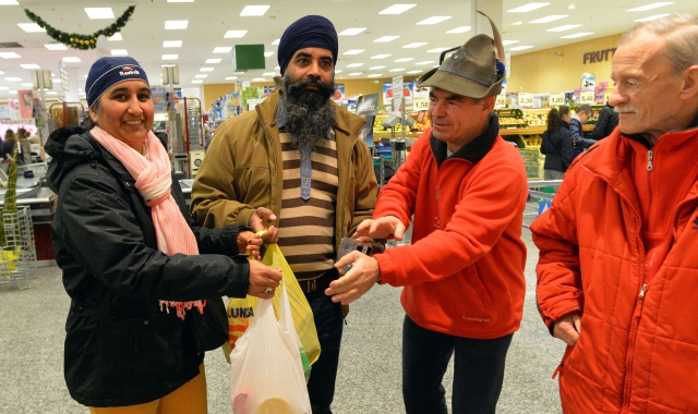 Una coppia di immigrati dona la spesa ai volontari della Colletta alimentare (foto Blitz)