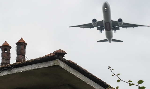Un aereo sorvola a poca distanza dal tetto di una casa il cielo attorno a Malpensa