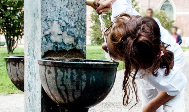 Una ragazza si disseta a una fontanella nelle ore della canicola (foto Blitz)