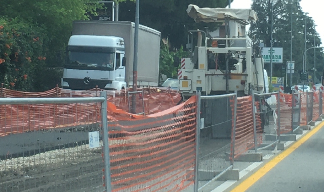 Il cantiere aperto sulla Saronnese: auto e camion passano ai lati, gli operai lavorano in mezzo (foto Pubblifoto)