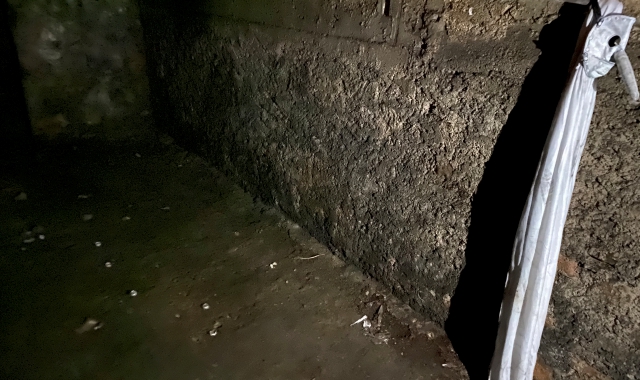 Il mantello bianco e la maschera con un lungo naso appesi a un gancio di metallo in un capannone abbandonato in via Bainsizza (foto Blitz)
