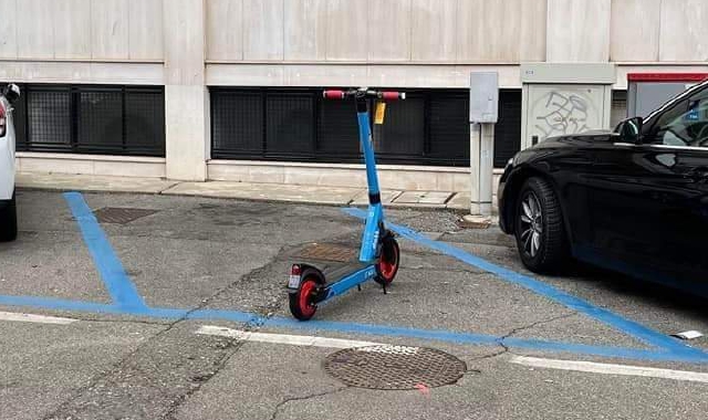 Un monopattino che occupa un parcheggio blu