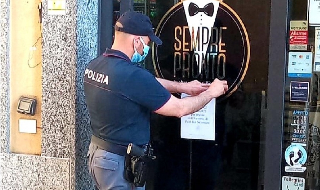Un agente affigge l’ordine di chiusura (foto Polizia di Stato)