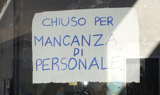 Il cartello affisso in una nota vineria del centro, colpita dalla mancanza di personale
