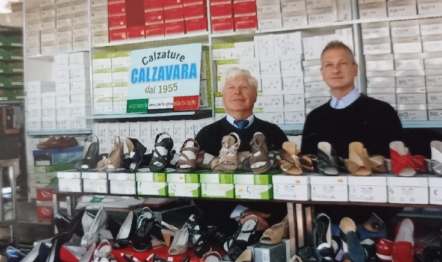 Rodolfo Calzavara ( a destra) con il padre al loro banco di vendita di scarpe, che ogni settimana espone a Luino, Varese e Milano