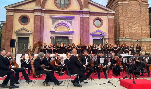 Orchestra e coro durante la serata legnanese: sullo sfondo la basilica di San Magno