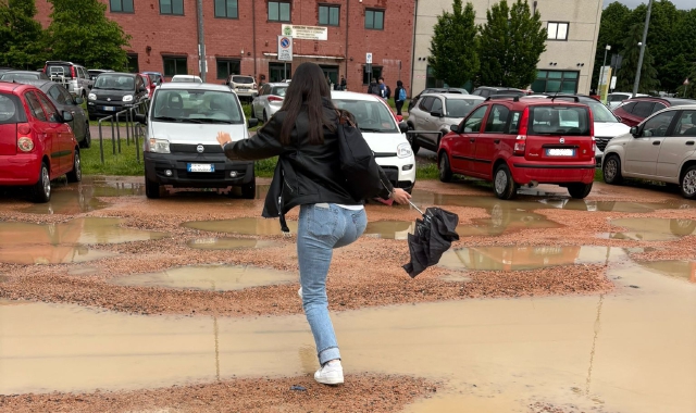 Una studentessa fa lo slalom tra le pozzanghere nel parcheggio davanti al padiglione Monte Generoso dell’università