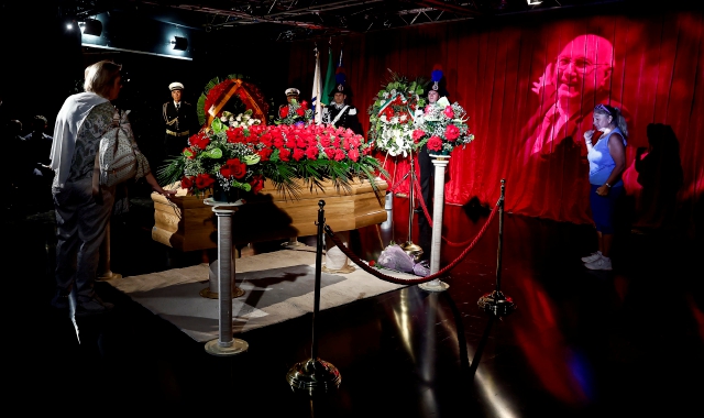 Il feretro sul fondo di un sipario rosso è circondato da rose rosse e su uno schermo televisivo scorrono immagini della carriera di Baudo, proiettate anche all’entrata (foto Angelo Carconi/ANSA)